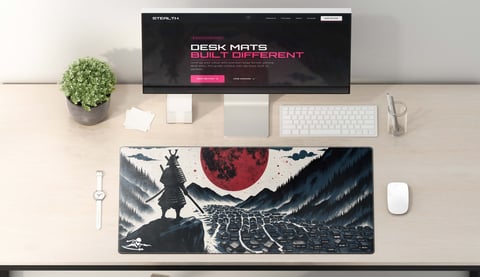 Desk setup with monitor displaying desk mat website, keyboard, mouse, and decorative desk mat featuring samurai warrior artwork